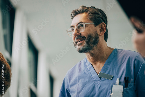 Low angle view of smiling mature male doctor wearing eyeglasses at hospital