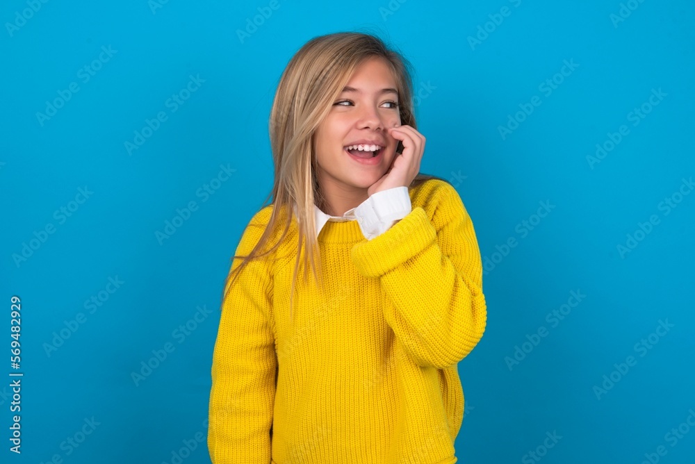 caucasian teen girl wearing yellow sweater over blue studio background hear incredible private news impressed scream share caucasian teen girl wearing yellow sweater over blue studio background hear incredible private news impressed scream share
