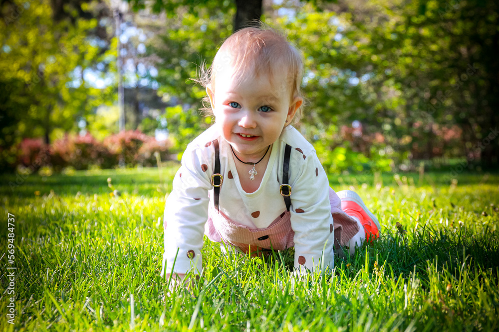baby in the grass. little child playing in the park. A girl child rejoices on the grass. A little girl on the green grass. Cute toddler on green grass. baby in the grass. little child playing in the park. A girl child rejoices on the grass. A little girl on the green grass. Cute toddler on green grass.