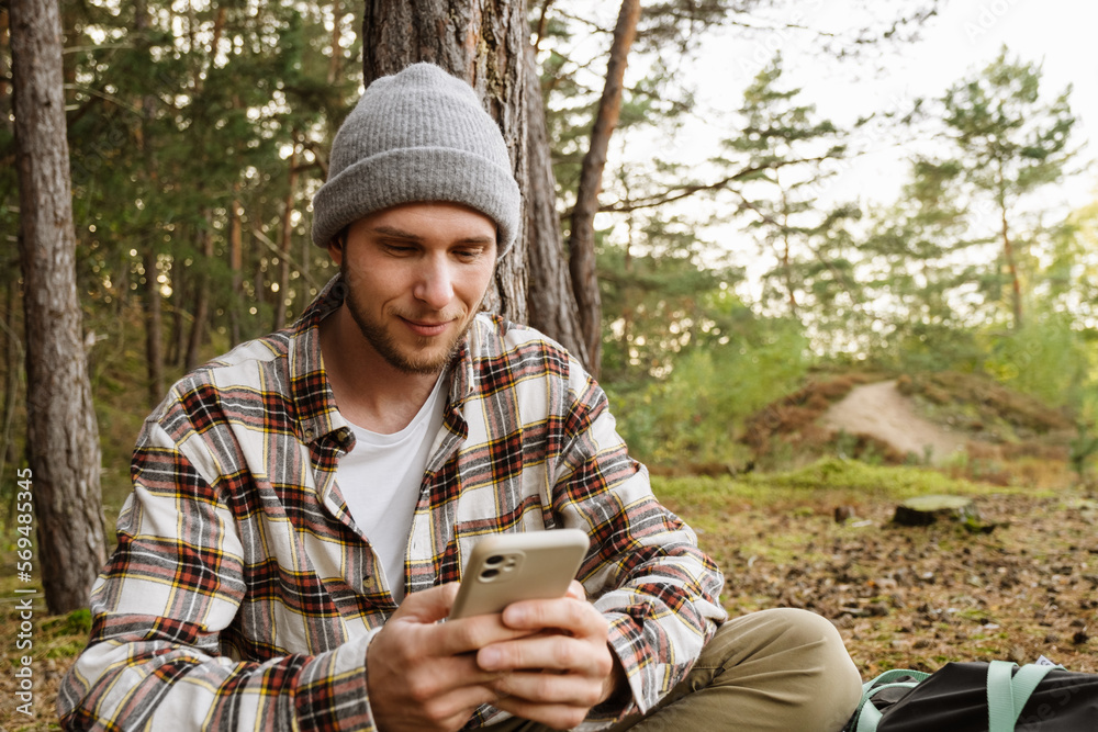 Young man using mobile phone while sitting in forest Young man using mobile phone while sitting in forest