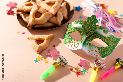 Purim table with hamantaschen cookies, carnival mask, holiday decor in hard light