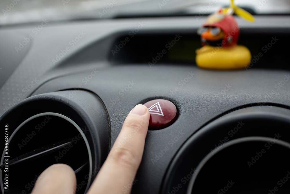 Pressing the emergency button in the car.Car alarm.Finger on the button. Traffic accident.Car breakdown.Alarm.Rubber duck in the auto.Yellow rubber duck.Car interior. Dashboard.Automotive. Pressing the emergency button in the car.Car alarm.Finger on the button. Traffic accident.Car breakdown.Alarm.Rubber duck in the auto.Yellow rubber duck.Car interior. Dashboard.Automotive.