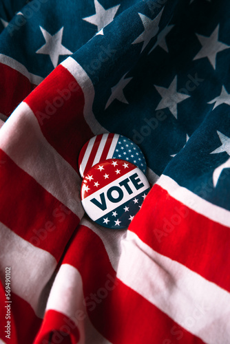 Political vote, election pin on American flag. Black background.