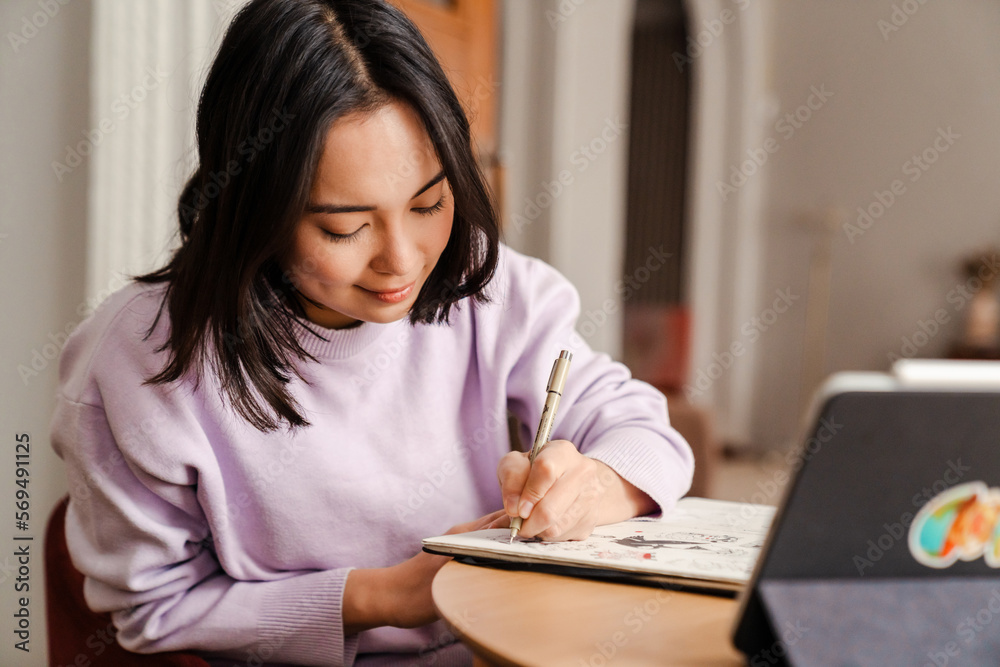 Beautiful asian woman drawing while sitting in living room Beautiful asian woman drawing while sitting in living room