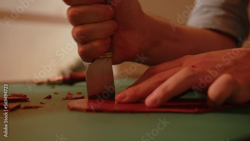 Artisan shoemaker processes piece of leather with saddlery knife. Craftsman making handmade shoes.