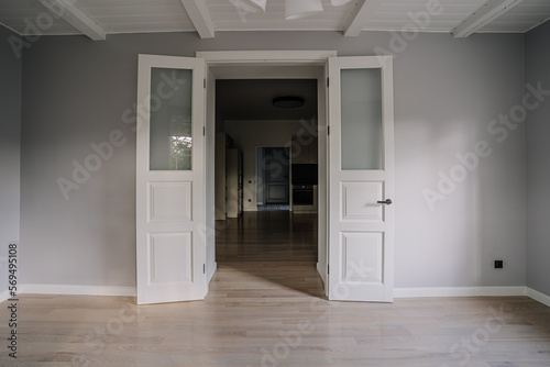 Classical empty room interior. The rooms have wooden floors and gray walls  decorate with white moulding there are white window looking out to the nature view.