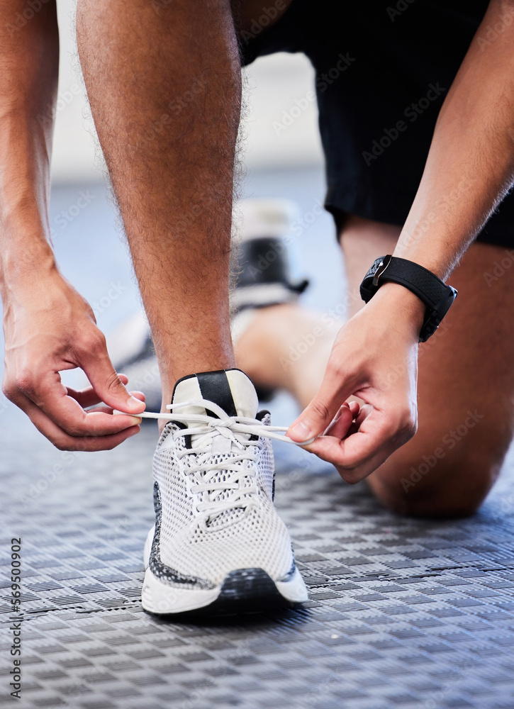 Shoes, runner and man getting ready for training, exercise or running in sports sneakers, fashion and foot on floor. Feet of athlete or person tying his laces for cardio, fitness or workout in gym