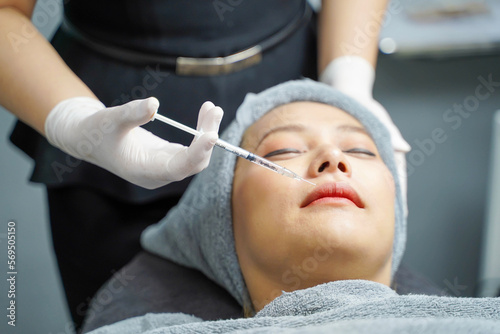 Closeup hands of beauty doctor in medical grove holding beauty skin syringe injecting the customer s face. Beauty skin concept