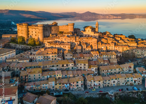Sunset Panoramic view of the old town of Bracciano perched above the calm waters of Lake Bracciano, near Rome, Italy - Orsini-Odescalchi castle, Duomo and village lit by the golden hour light