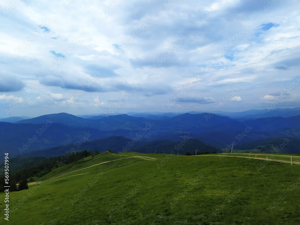 Green summer mountain landscape. Dirt road, footpath at the top of the peak.