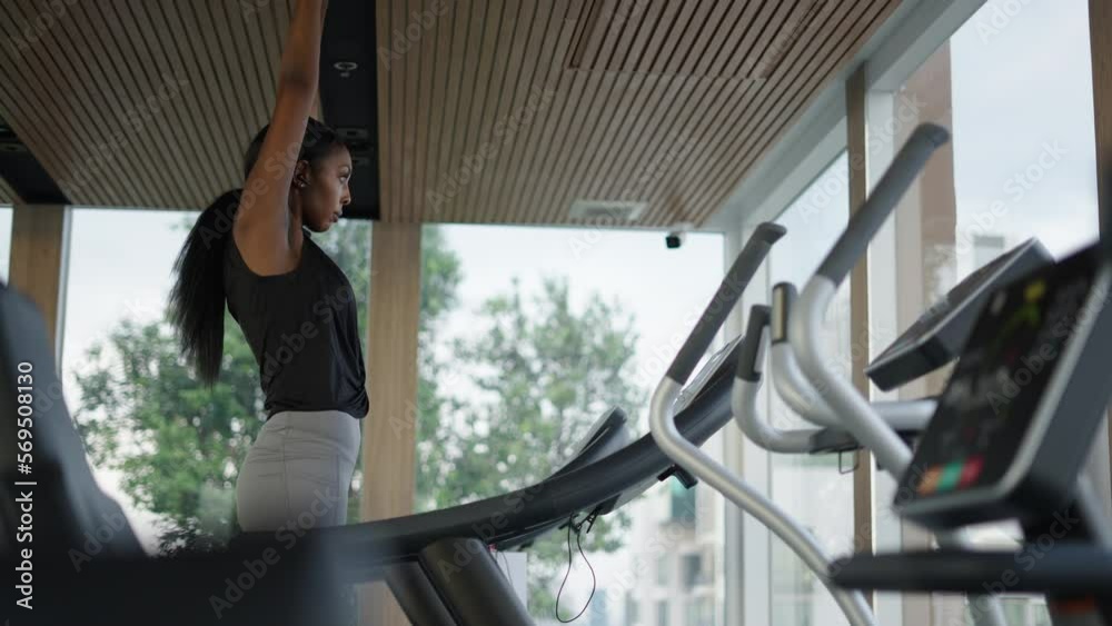 Black digital nomad stretching in a treadmill looking the skyline through a window Black digital nomad stretching in a treadmill looking the skyline through a window