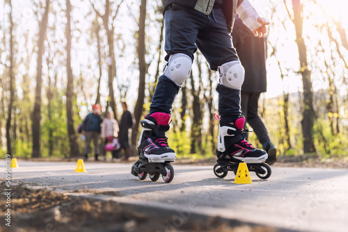 Group of little children enjoy having fun learning inline roller skate slalom with plastic cones on road in city park outdoors on sunny spring day. Healthy kid outside sport exercise activities © Kirill Gorlov