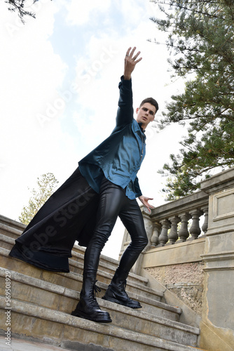 portrait of handsome brunette male model wearing fantasy medieval prince costume, romantic silk shirt. Wandering around historical castle location background with stone staircase. © faestock