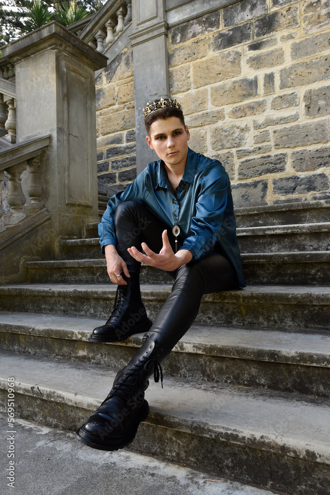 portrait of handsome brunette male model wearing fantasy medieval prince costume, romantic silk shirt. Wandering around historical castle location background with stone staircase.