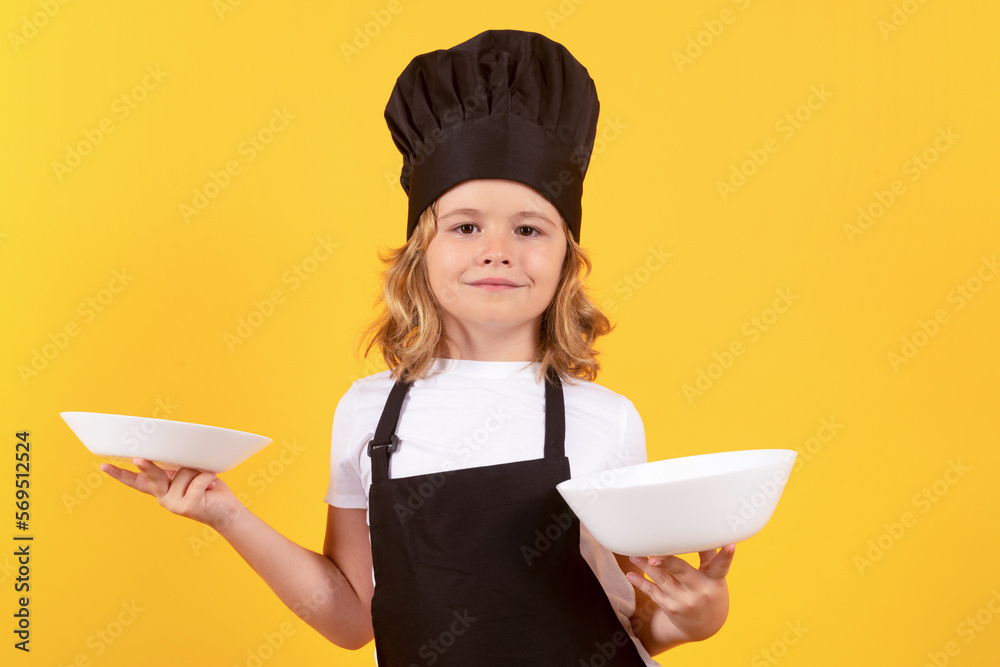 Little cook with cooking plate. Child chef cook. Child wearing cooker uniform and chef hat preparing food, studio portrait. Little cook with cooking plate. Child chef cook. Child wearing cooker uniform and chef hat preparing food, studio portrait.