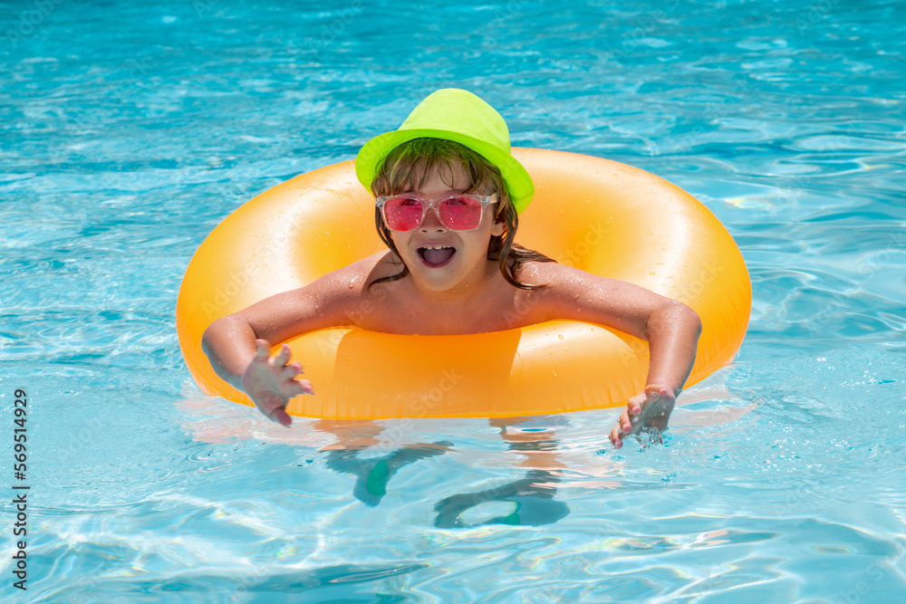 Child boy in swimming pool with inflatable toy ring. Kids swim on summer vacation. Swim for child on float. Beach sea and water fun.
