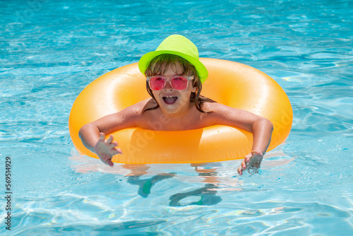 Child boy in swimming pool with inflatable toy ring. Kids swim on summer vacation. Swim for child on float. Beach sea and water fun.