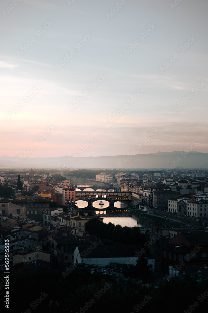 Florence city view from Michelangelo square at sunset. Vertical shot, Blue and red sky, misty, foggy background. Florence, Tuscany, Italy. Ponte Vecchio bridge.
