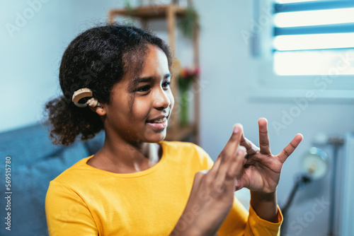 Beautiful smiling black deaf girl using sign language at home photo