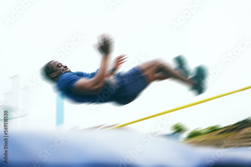 Athletics, fitness and high jump by man at a stadium for training, energy and cardio with blur and speed. Jumping, athlete and male outdoors for performance, endurance and competition on mock up