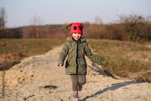 Cute little girl having fun in nature. A beautiful child poses outdoors on a sunny day in early spring.