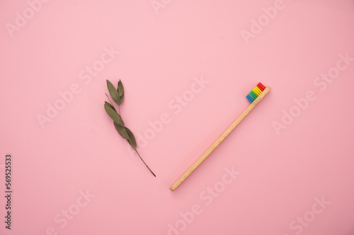 Eco-friendly bamboo toothbrush, dental cleaner and a green leaf on a pink background. © Anastasia