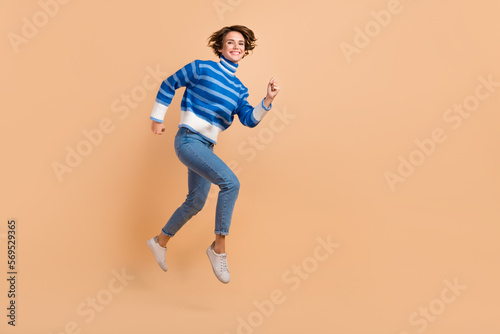 Full length portrait of active energetic person jumping rush empty space isolated on beige color background