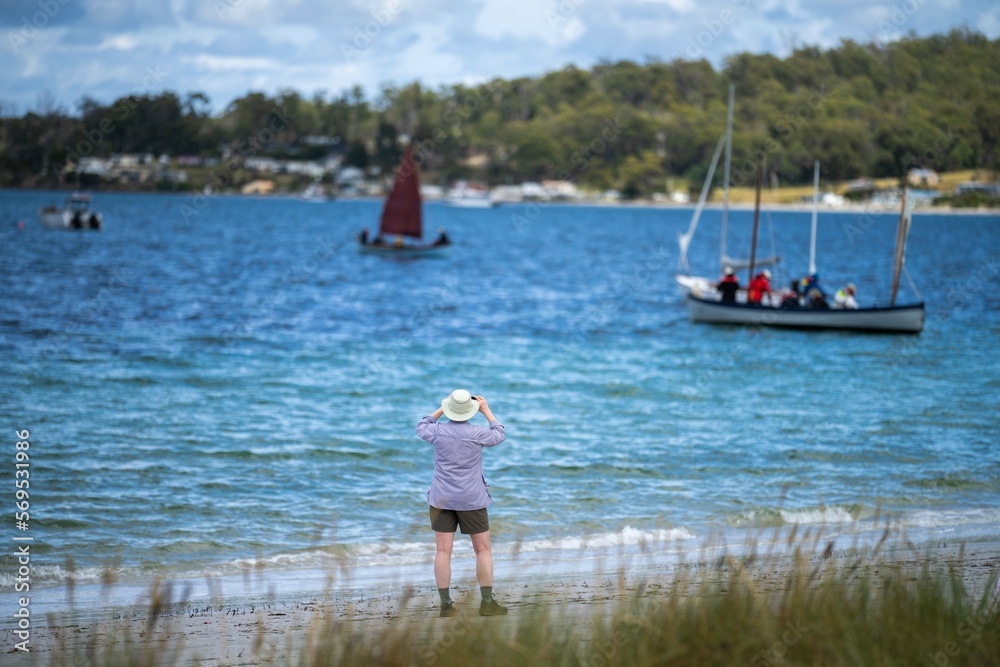 man watching wooden boat on the water, at the wooden boat festival in hobart tasmania australia