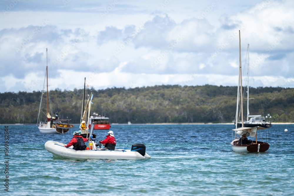 Fototapeta premium man watching wooden boat on the water, at the wooden boat festival in hobart tasmania australia