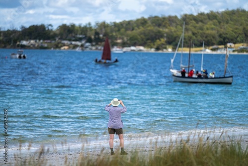 man watching wooden boat on the water, at the wooden boat festival in hobart tasmania australia © Phoebe