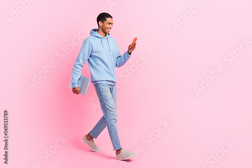 Full length photo of attractive glad man user blogger wear trendy clothes go work typing sms empty space isolated on pink color background © deagreez