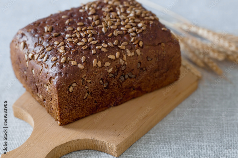 Fresh delicious whole grain rye bread with seeds close-up. Freshly baked bread on a wooden board. The context of a bakery with delicious bread. Confectionery products. Fresh delicious whole grain rye bread with seeds close-up. Freshly baked bread on a wooden board. The context of a bakery with delicious bread. Confectionery products.