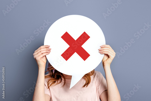 Girl holding poster with a prohibition cross sign isolated on a gray background