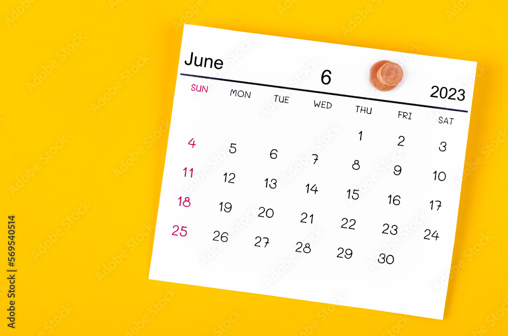 A June 2023 calendar and wooden push pin on yellow background. A June 2023 calendar and wooden push pin on yellow background.