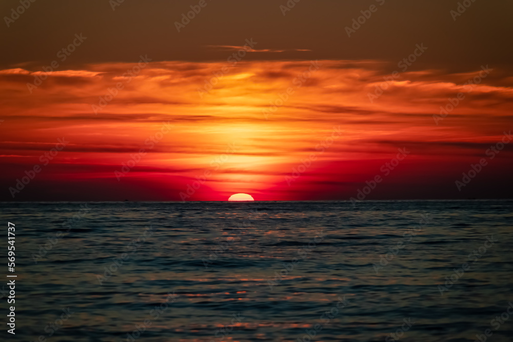 Panoramic sunset view from Sveti Stefan at Adriatic Mediterranean Sea, Budva Riviera, Montenegro, Europe. Reflection of sun beams on water surface during twilight. Summer vacation in seaside resort
