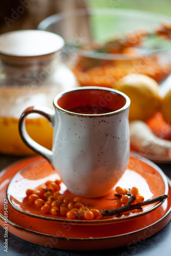 Sea buckthorn tea. Still life cup with tea, berries and lemons. Orange sea buckthorn drink, juice. Autumn mood.
