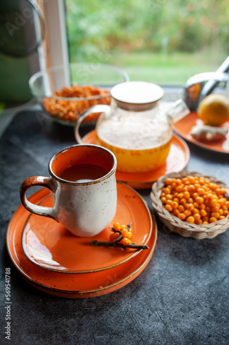 Sea buckthorn tea. Still life cup with tea, berries and lemons. Orange sea buckthorn drink, juice. Autumn mood.
