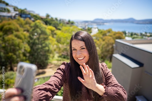 Girl video calling her friends on a zoom call. Woman on holiday skyping her family outside in a beautiful place photo