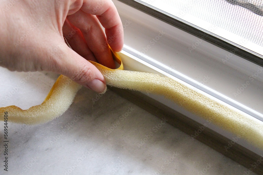 Fototapeta premium applying sponge tape or window seal to the PVC window for heat insulation