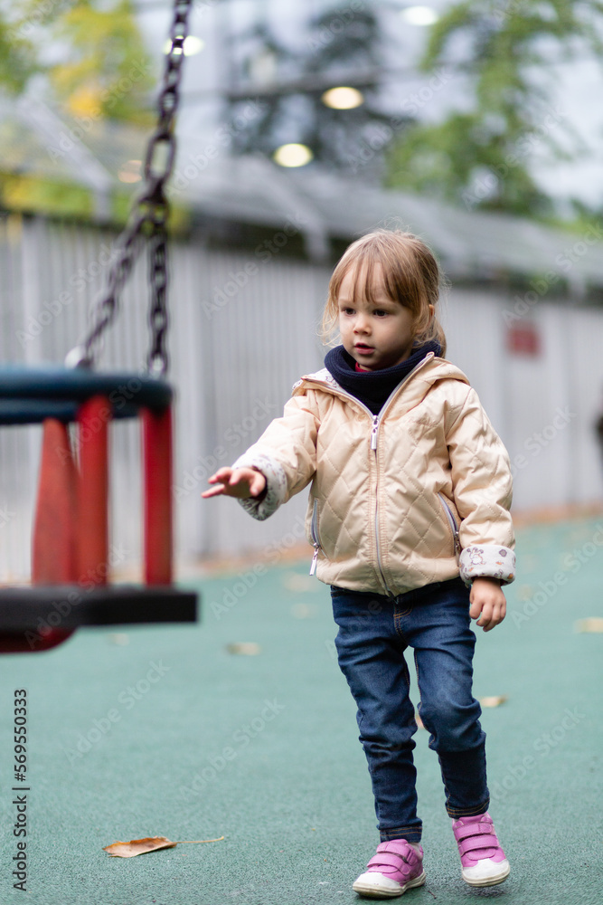 Little girl playing with swings at the playground