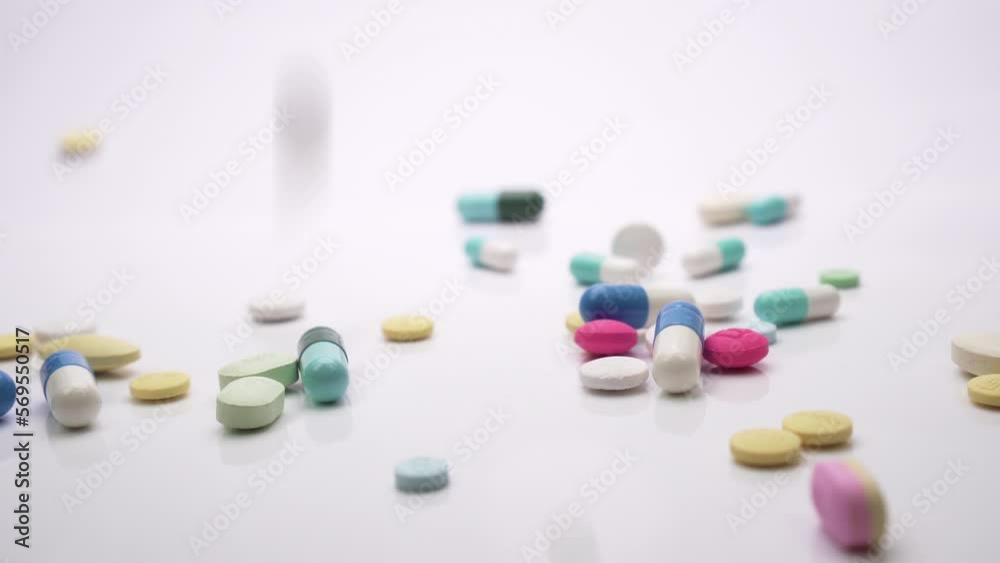 Slider shot of pills falling on white background.
Slider shot of pills falling on white background.