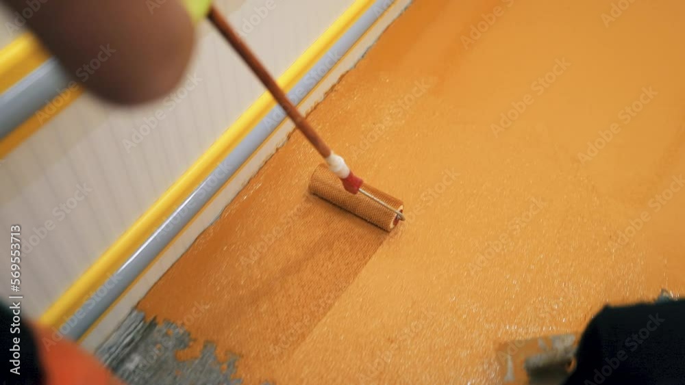 A construction worker apply epoxy resin in an industrial hall A construction worker apply epoxy resin in an industrial hall