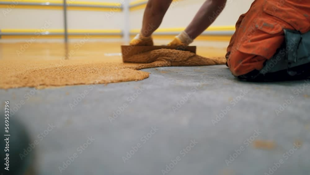 The worker applies yellow epoxy resin on the new floor The worker applies yellow epoxy resin on the new floor