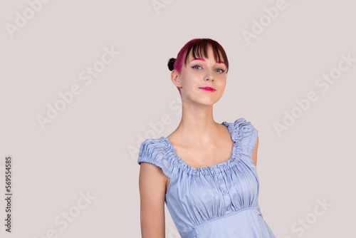 smiling teenager girl in a blue dress looks into the frame on a light background