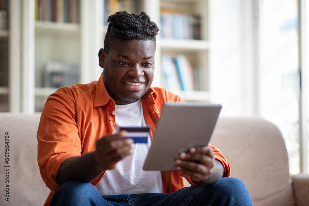 Cheerful african man using digital pad and credit card Cheerful african man using digital pad and credit card