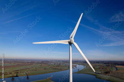 Contrasting closeup of wind turbine and against clear blue sky in The Netherlands part of sustainable industry Dutch at intersection river IJssel and Twentekanaal waterway. Aerial circular economy.