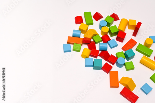 Colorful wooden bricks of different shapes on a white wooden table. The concept of learning. empty space