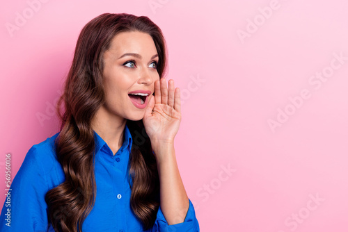 Portrait of good mood pretty nice girl wavy hairstyle wear blue shirt look empty space palm near cheek isolated on pink color background