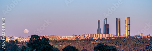 Sunset of the Madrid skyline with the towers of the financial area in the background and the moon rising at dusk