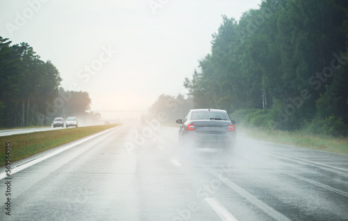 a passenger car is driving on a slippery highway from the rain. Heavy fog and rain on the highway. Bad visibility. Copy space for text © HENADZY